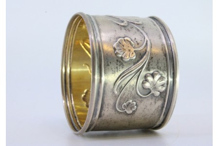 Argola de guardanapo em prata com figura de jovem e motivos florais relevados.